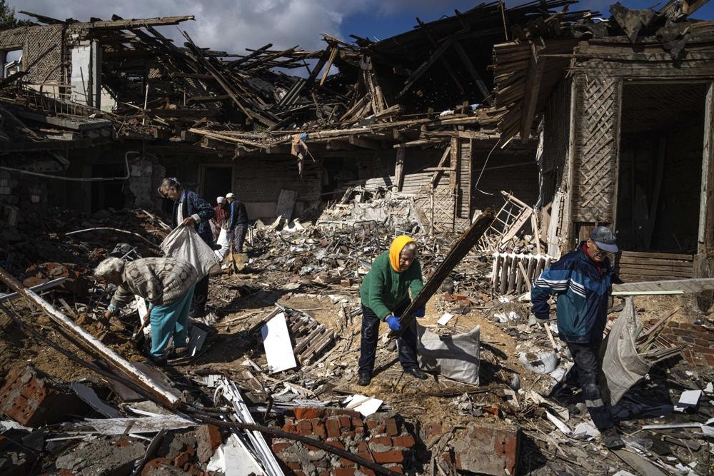 Local residents collect wood for heating from a destroyed school where Russian forces were based, in the recently retaken area of Izium, Ukraine, Monday, Sept. 19, 2022. Residents of Izium, a city recaptured in a recent Ukrainian counteroffensive that swept through the Kharkiv region, are emerging from the confusion and trauma of six months of Russian occupation, the brutality of which gained worldwide attention last week after the discovery of one of the world's largest mass grave sites. (AP Photo/Evgeniy Maloletka)